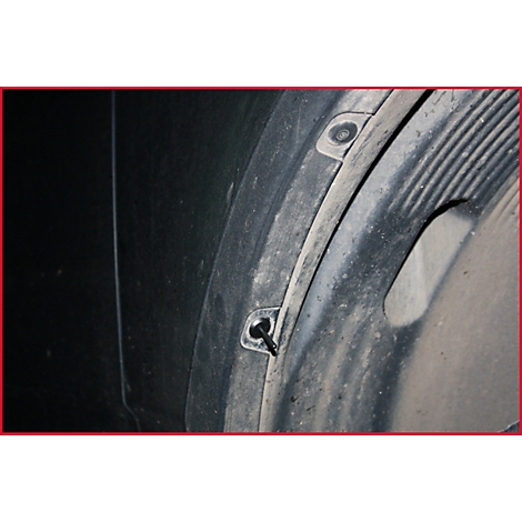 Nahaufnahme eines schwarzen Kotflügels mit Schrauben und schmutziger Innenfläche.